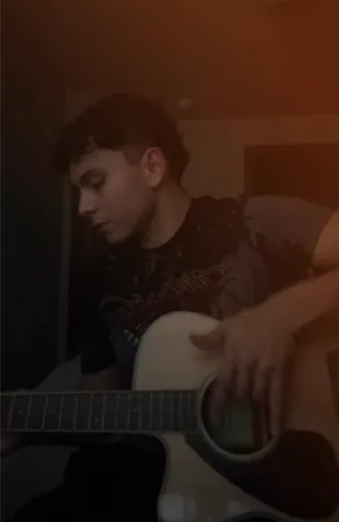 Joven cantando mientras toca la guitarra